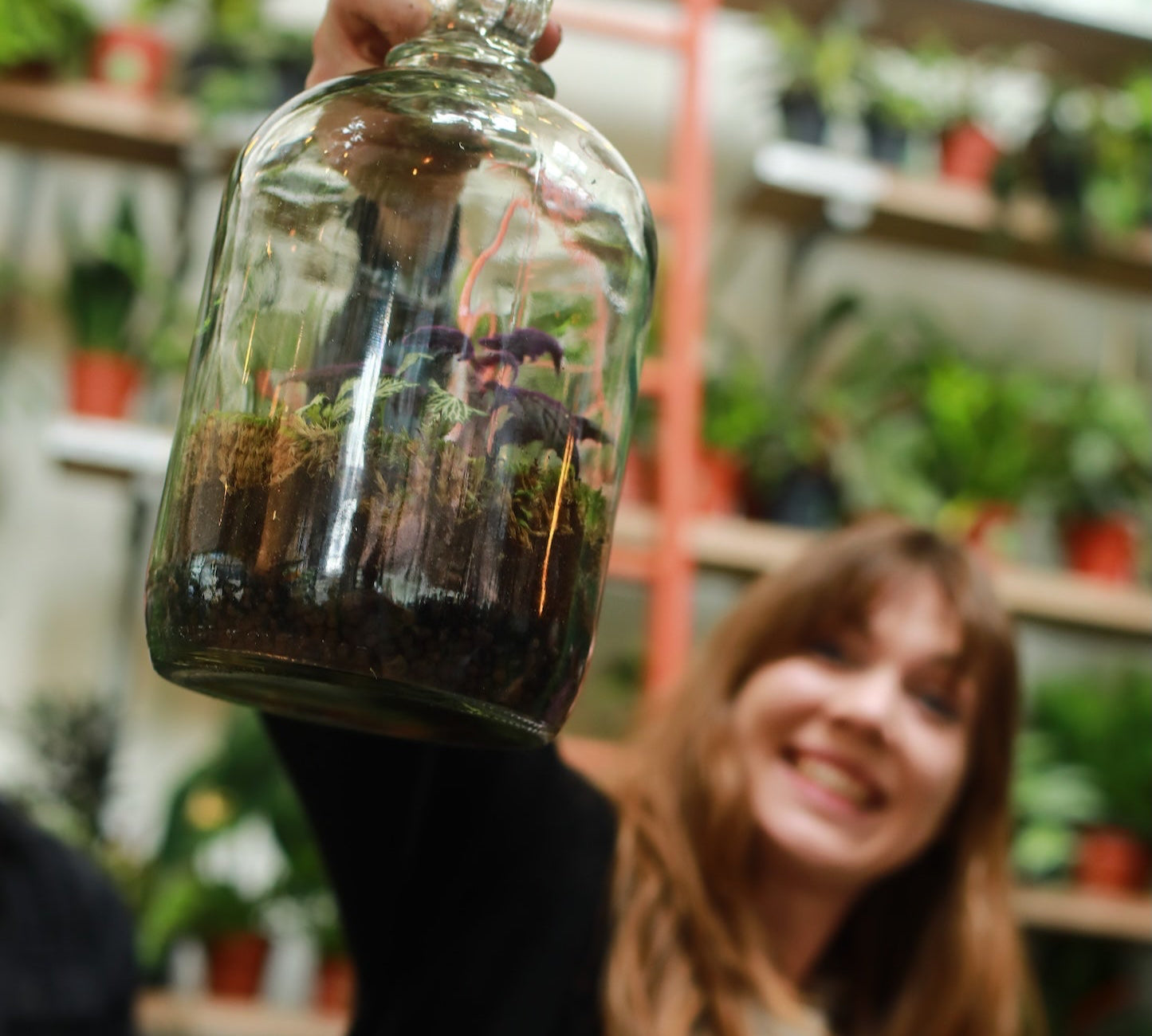 woman holding a completed demijohn terrarium